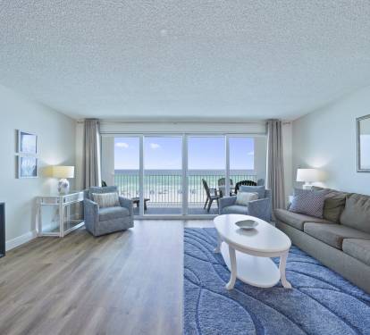 The coastal-inspired living space features comfortable seating, flat-screen TV, and floor-to-ceiling sliding doors to the beach balcony.