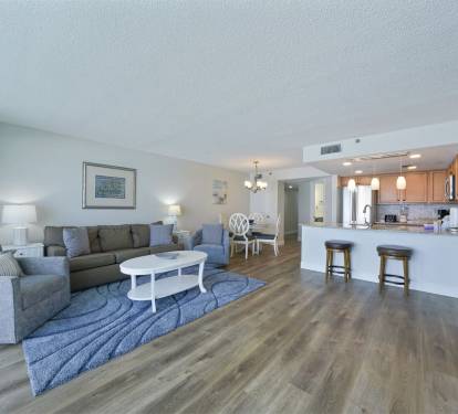 Spacious open-concept living room at Cabana Club 307 in Destin featuring coastal d-cor, comfortable seating, and a fully equipped kitchen with breakfast bar.