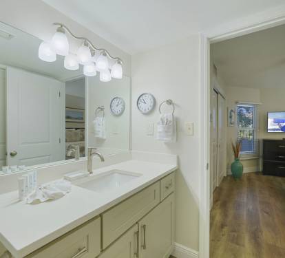 Bright coastal bathroom featuring a spacious vanity, large mirror, and soft lighting for a clean, refreshing feel. The convenient layout opens directly to the master bedroom.