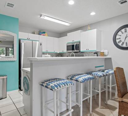 Kitchen bar with seating and coastal accents at Maravilla 4205.