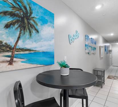 Hallway dining nook with tropical artwork and seating at Maravilla 4205, a Miramar Beach vacation rental near the Gulf.