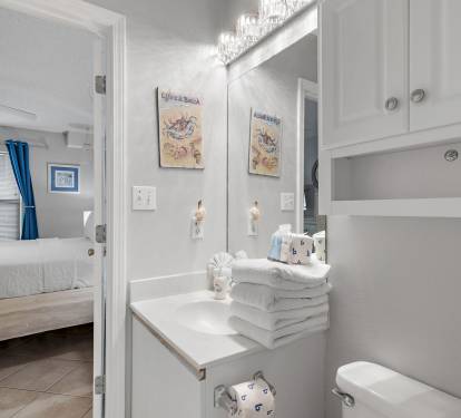 Bathroom with vanity, mirror, and coastal artwork at Maravilla 4205, a Miramar Beach vacation rental near the beach.
