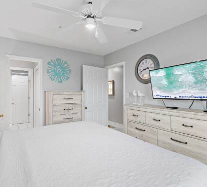 Bright guest bedroom with king bed, dresser, and TV at Maravilla 4205, a Miramar Beach condo rental.
