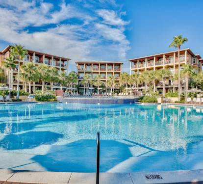 Large community pool surrounded by palm trees and lounge areas, offering a resort-style atmosphere for guests.