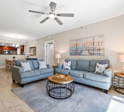 Open-concept living space with cozy sleeper sofa, large Smart TV, and beautiful natural light from the balcony access.