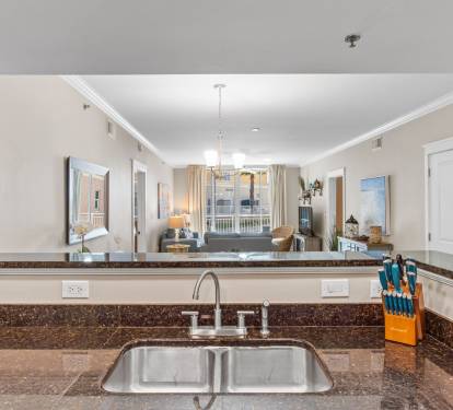 Open-concept kitchen with full amenities, breakfast bar seating, and sightlines to the dining room and balcony.