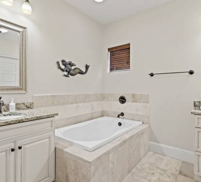 Spacious ensuite with soaking tub, double vanity, and elegant tile details.