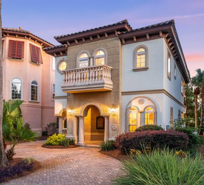 The stunning design aesthetic of Tuscan Charm with lush landscaping, arched windows, & circular driveway.