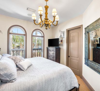 Arched windows provide natural light into this primary king bedroom with spacious walk-in closet and a 42" smart tv.