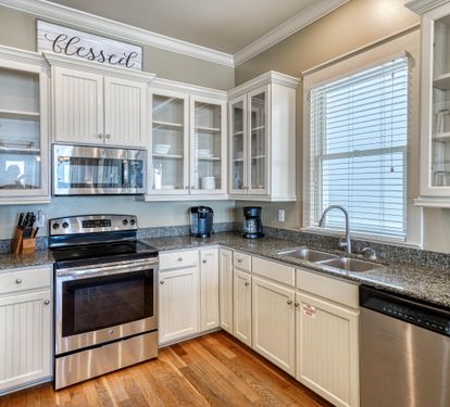 Open Kitchen with Granite Countertops, Stainless Steel Appliances, & Custom Cabinetry Stocked with Cookware & Dinnerware