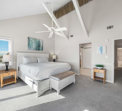 Lofted ceiling with white beams give this primary king bedroom a light and airy feel.