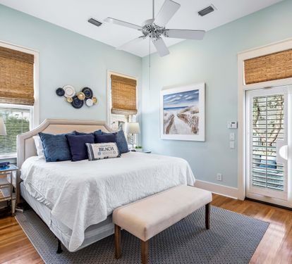 Hardwood floors, woven shades plus plantation shutters give this primary bedroom a sense of sophistication and serenity.