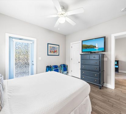 Another view of the first floor bedroom with a queen bed,42" tv, large walk-in closet, additional door out to the front porch, and a full bathroom.