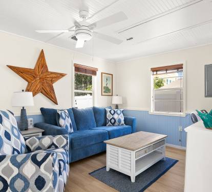 Sunlight fills this inviting living space with soft coastal hues, comfortable seating, and casual furnishings ideal for unwinding after a day by the shore.