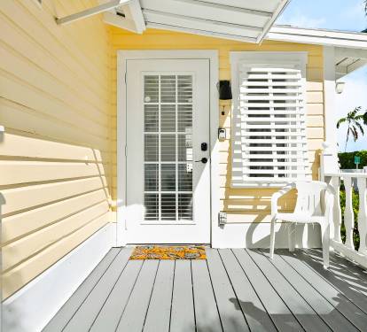 Nestled among palms, this cozy single-story bungalow features a shaded front porch and coastal-style shutters just steps from sandy shores.