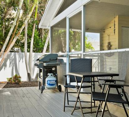 This tropical backyard features a private swimming pool, a built-in grill, and lush palm landscaping—perfect for relaxing outdoor meals after a beach day.