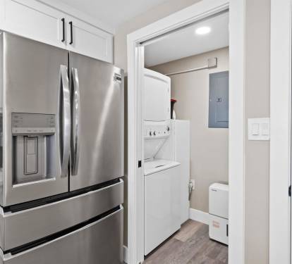 Your modern kitchen flows seamlessly into a convenient laundry space, featuring stainless steel appliances and pristine white cabinetry for effortless meal prep and housekeeping.