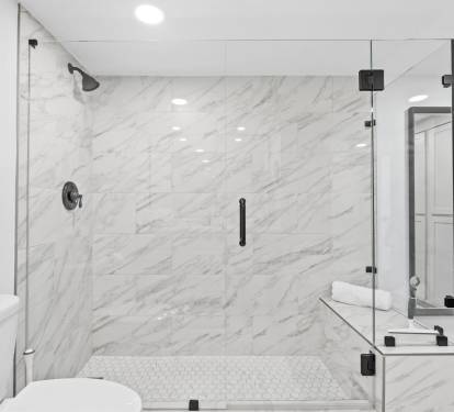 Step into your luxurious marble bathroom featuring a stunning glass-enclosed shower with rainfall head and elegant built-in seating bench.