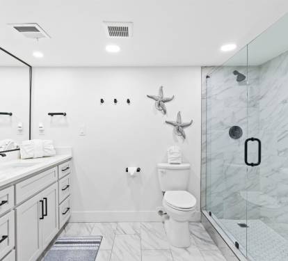 Step into your luxurious marble sanctuary featuring a spacious walk-in shower and elegant coastal touches that make every morning feel like a spa retreat.