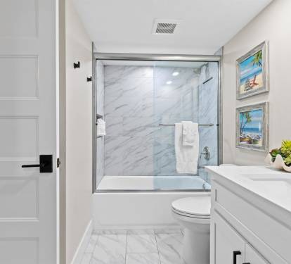 Step into your spa-like bathroom featuring elegant marble shower, pristine finishes, and coastal artwork that sets a peaceful tone for your morning routine.