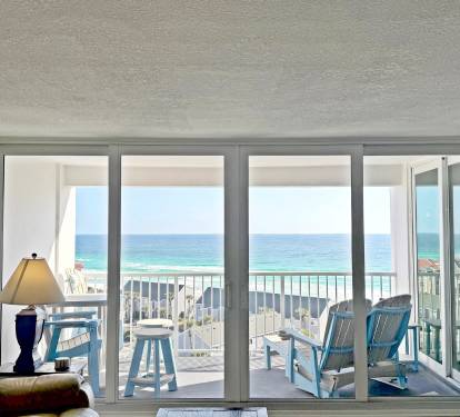 Step into your beachfront haven where floor-to-ceiling windows frame endless ocean views and your private balcony awaits with comfortable seating.