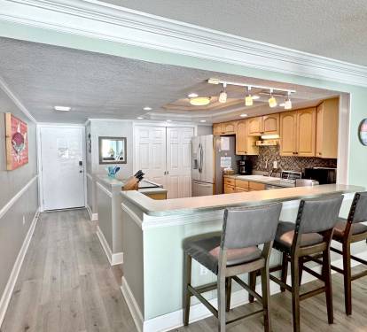 Your open-plan kitchen features warm wood cabinets, granite counters, and a breakfast bar where you can enjoy morning coffee or casual meals together.
