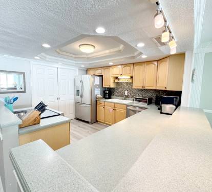 Your fully equipped kitchen invites culinary adventures with granite counters, stainless appliances, and modern track lighting creating the perfect cooking atmosphere.