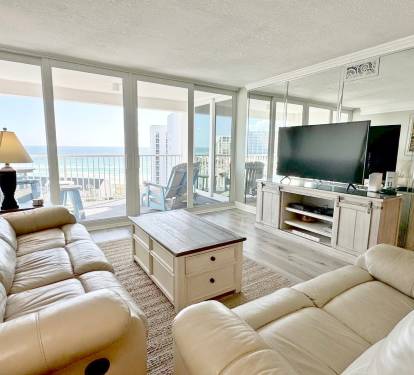 Your stunning corner living room wraps you in comfort with plush recliners while panoramic windows showcase breathtaking ocean and city views.