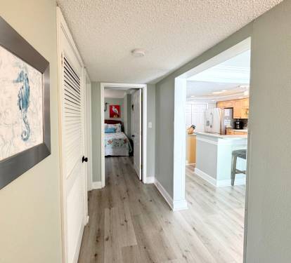 You'll love the open flow connecting your private hallway to the bright, modern kitchen with coastal artwork guiding your way.
