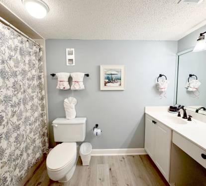 Refresh in your thoughtfully designed bathroom with elegant floral curtains, coastal artwork, and charming towel origami touches.