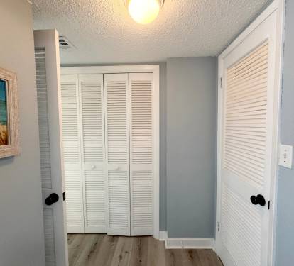 Step into your serene hallway with coastal charm - white louvered doors and beachy artwork create a peaceful transition to your restful retreat.