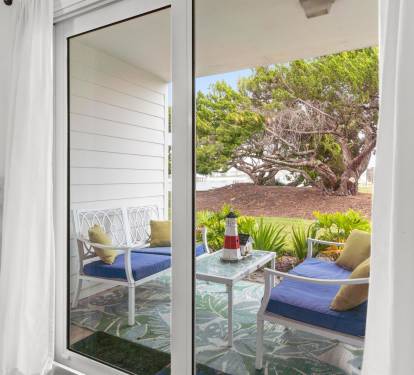 Step through glass doors onto your private patio, where cozy seating awaits beneath mature trees and tropical landscaping.