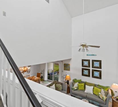 Relax in your spacious living room with soaring ceilings and tropical views, where coastal breezes and comfortable seating create the perfect retreat.