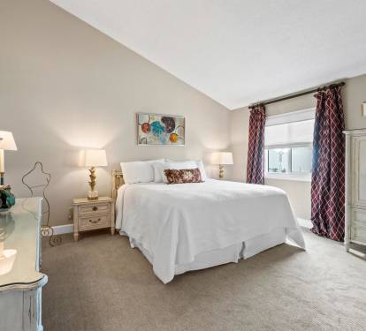 Sink into plush white bedding in your elegant bedroom sanctuary, complete with warm lighting and thoughtful furnishings for ultimate comfort.