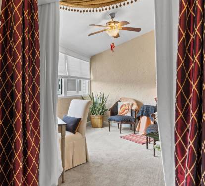 Step into your cozy living space where elegant patterned curtains frame comfortable seating and warm touches await your arrival.