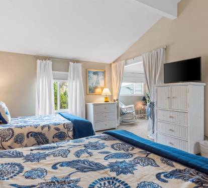 Relax in your coastal-inspired twin bedroom with soft blue linens, warm natural light, and peaceful garden views through your windows.