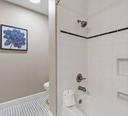 Unwind in your sparkling clean bathroom featuring a pristine tub-shower combo and thoughtful touches like fresh towels and elegant tile work.