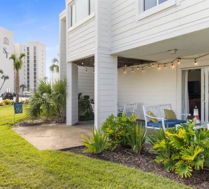 Unwind on your private patio with comfortable seating and twinkling lights, surrounded by tropical landscaping and peaceful beach town views.