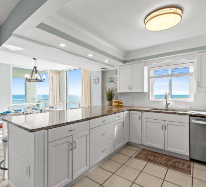 Your dream kitchen awaits with sparkling granite counters and breathtaking ocean views stretching endlessly beyond floor-to-ceiling windows.