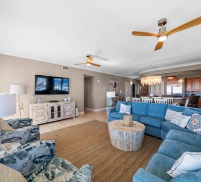 Unwind in your spacious living area where coastal blues meet comfort—plush seating, entertainment center, and ceiling fans create the perfect retreat.