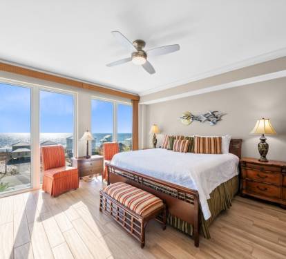 Your beachfront bedroom offers stunning sea views through floor-to-ceiling windows, with coastal breezes from the ceiling fan creating perfect relaxation.