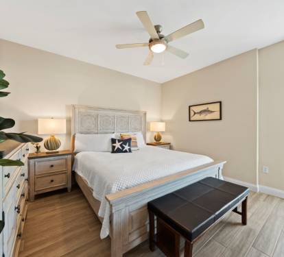 Unwind in your serene bedroom with coastal charm, featuring a plush bed and private balcony access for fresh morning air.