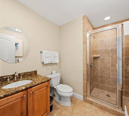 Refresh in your elegant bathroom featuring a spacious glass shower, granite counters, and warm tile finishes.
