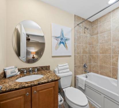 Your private bathroom features granite counters, fresh towels, and a relaxing tub-shower combo with coastal artwork to set the mood.