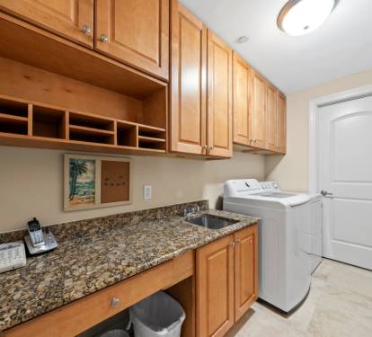Your dedicated laundry space features warm wood cabinetry, granite counters, and built-in storage cubbies to keep everything organized.