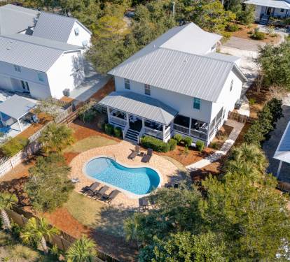This spacious beach house features a stunning kidney-shaped pool surrounded by tropical landscaping in a peaceful residential neighborhood.