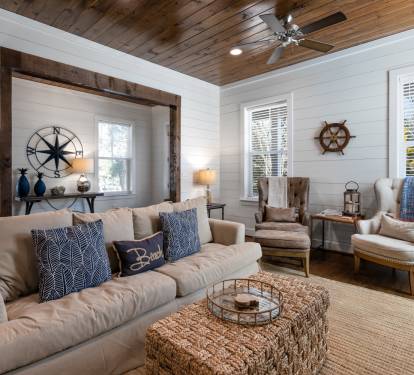 Sink into your cozy coastal living room featuring nautical touches and warm wood ceiling.