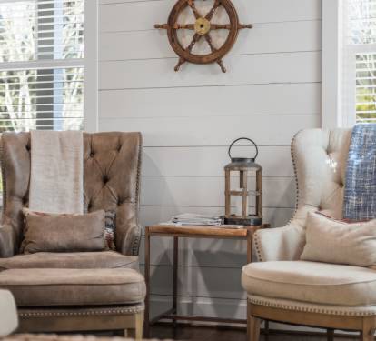 Sink into plush wingback chairs by bright windows where natural light and coastal charm create your perfect reading retreat.