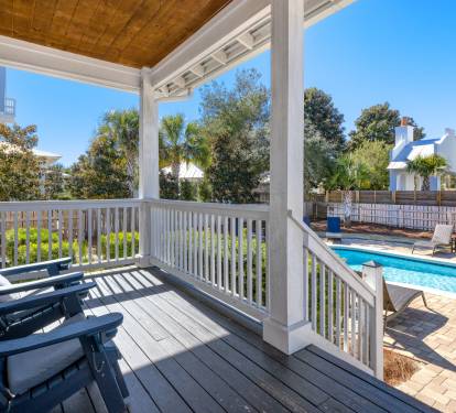 Your private covered porch overlooks the sparkling pool, perfect for morning coffee or evening relaxation with those comfy blue Adirondack chairs.