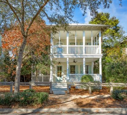 Charming Southern-style home featuring double-story wraparound porches and peaceful tree-lined street location.